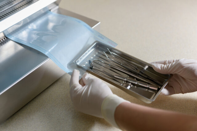 Sterilization of dental medical instruments. Dental assistant packs dental equipment into plastic bags for sterilization using a sterilization roll packaging machine for sterilized dental instruments.